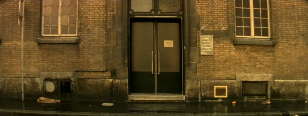 I Stand Alone (Seul Contre Tous) (1998) movie still: establishing — A brick building facade features a central double door with dark panels. The…