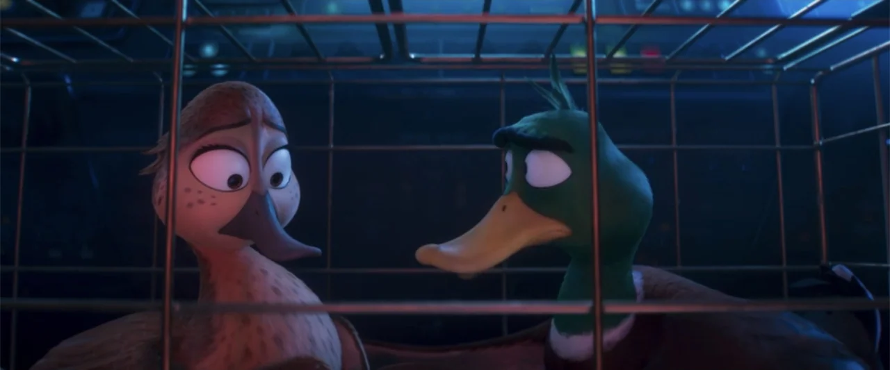 Migration (2023) movie still: medium — Two animated ducks are enclosed within a dark metallic bird cage indoors. The ducks face each other while…