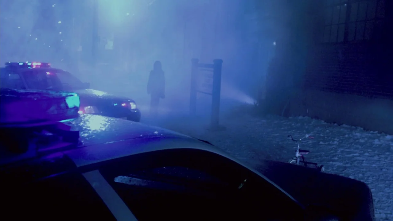 Saw VII: The Final Chapter (2010) movie still: wide — A nighttime scene in a paved lot obscured by thick artificial fog and light. A lone figure…