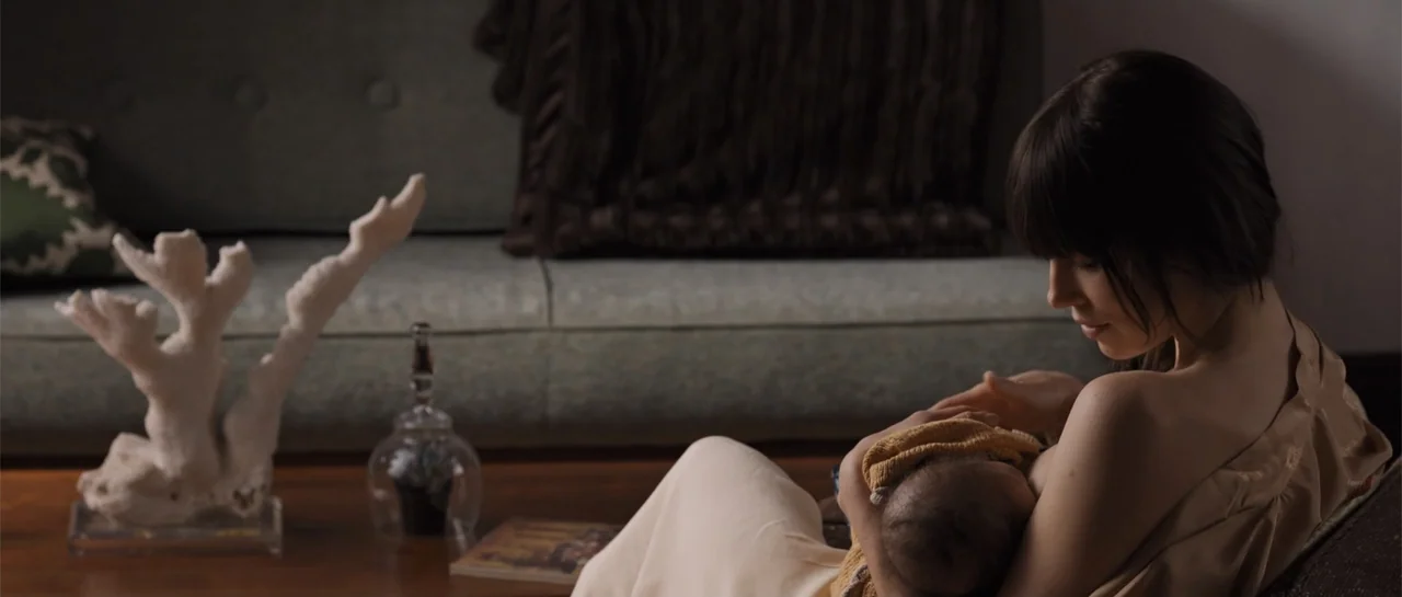 The Truth About Emanuel (2013) movie still: medium — A furnished interior features a sofa and a wooden coffee table with decor items. A woman sits…
