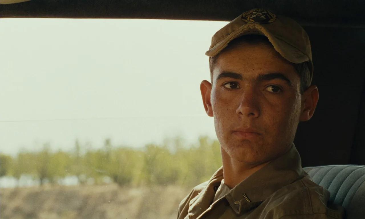 Taste of Cherry (1997) movie still: medium — A man sits inside a vehicle with a view of a desert landscape outside. He is positioned near the window…