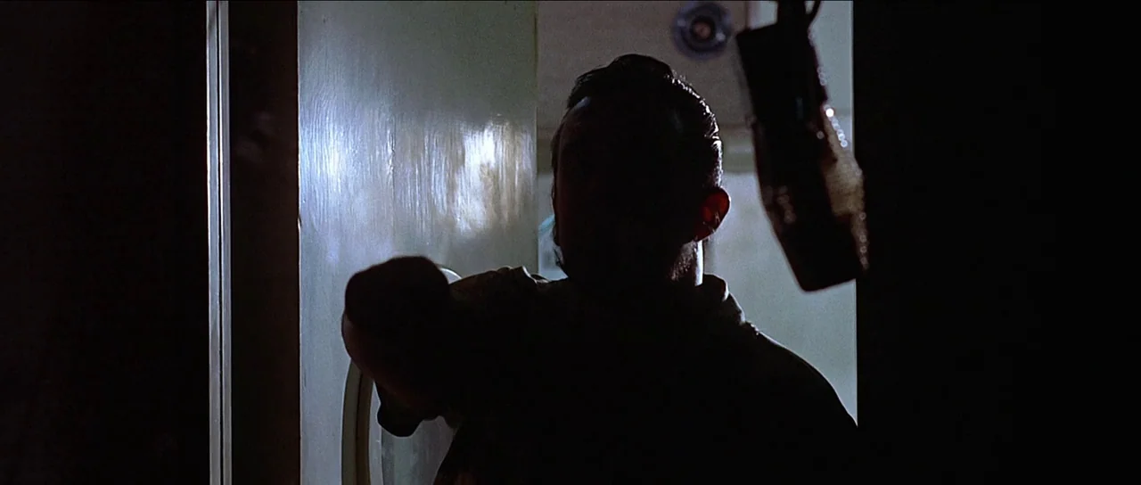 American Graffiti (1973) movie still: medium — A dimly lit room features a person silhouetted against a bright doorway. The subject extends their…