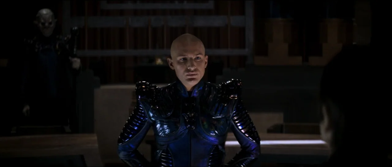Star Trek: Nemesis (2002) movie still: medium — A dark, expansive hall features stone architecture and low-level lighting elements. A bald man in…