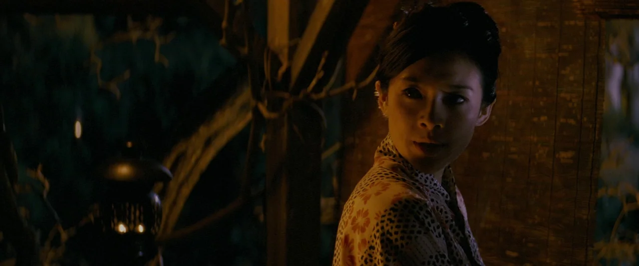Memoirs of a Geisha (2005) movie still: medium — A dark wooden outdoor space illuminated by a warm lantern in the night. A woman in a floral yukata…