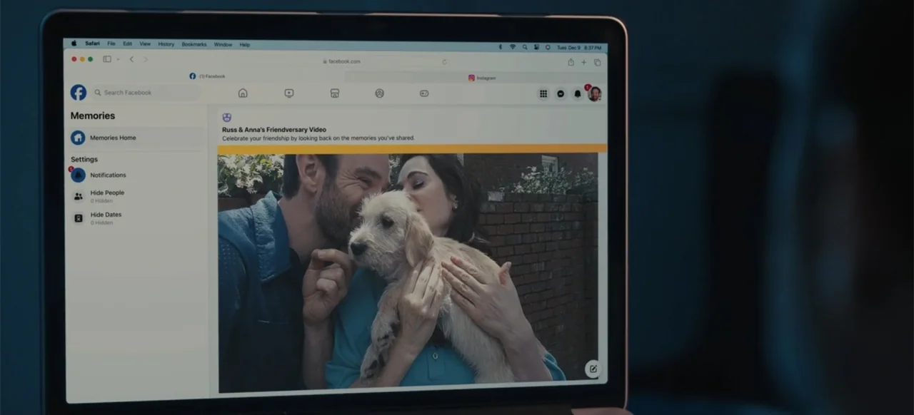 Merv (2025) movie still: closeup — A dark room contains a laptop displaying a Facebook memories page on the screen. The screen shows a photograph of…
