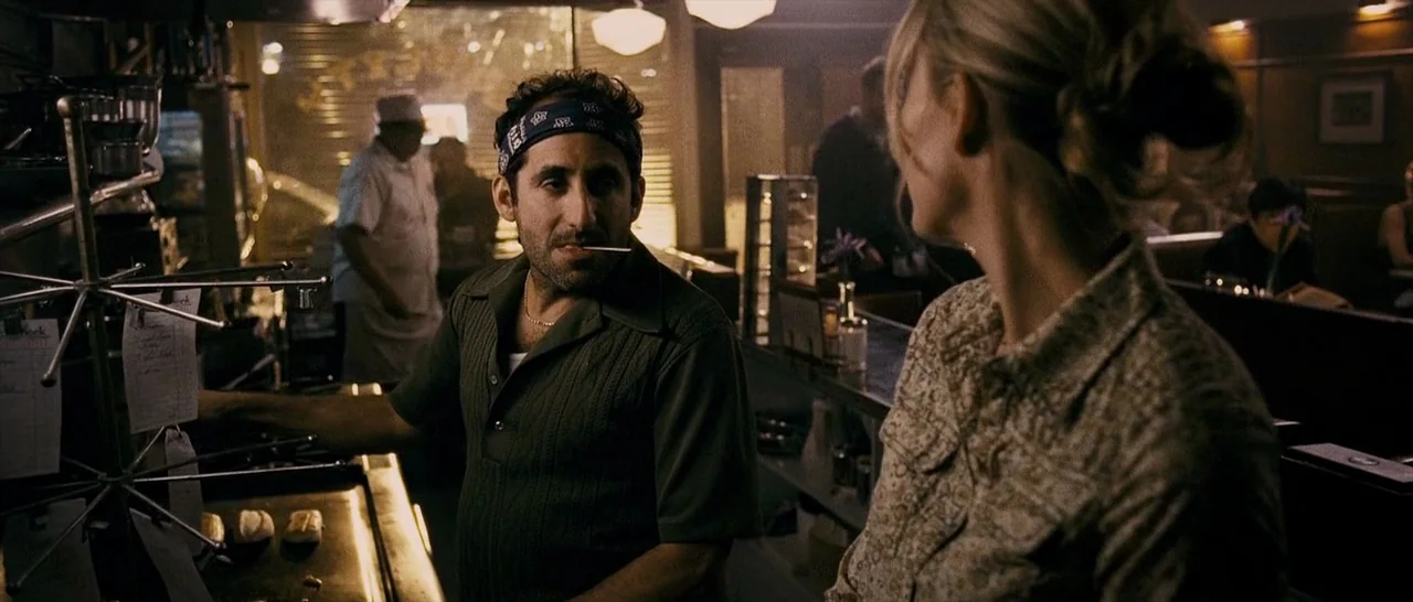 The Midnight Meat Train (2008) movie still: medium — A dimly lit diner features a counter service area with stainless steel surfaces and papers. A…