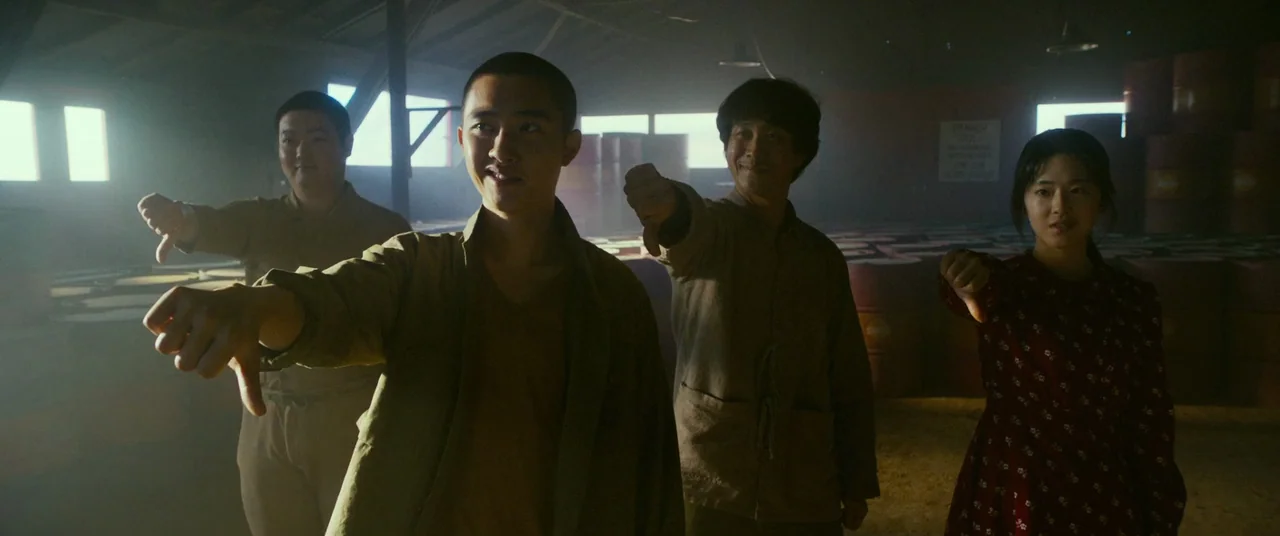 Swing Kids (2018) movie still: medium — A dusty barn interior filled with metal storage drums under backlight from rear windows. Four people stand…