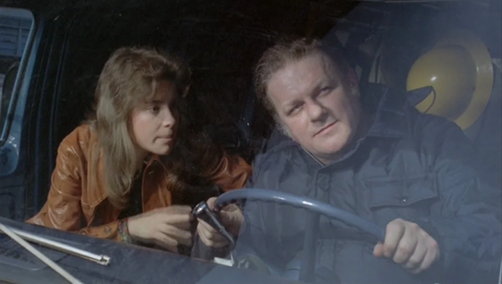 Sisters (1973) movie still: medium — The interior of a parked vehicle at night with dark surroundings. A woman speaks to a man who is holding the…