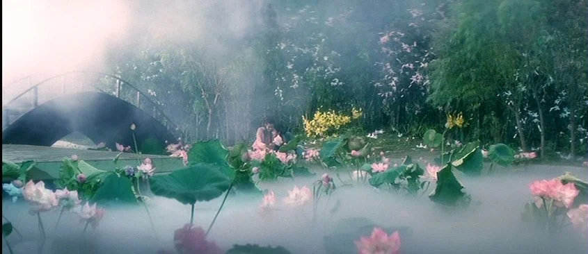 Green Snake (1993) movie still: wide — A dense pond filled with pink lotus flowers is covered in thick white fog. Two people are sitting on a wooden…