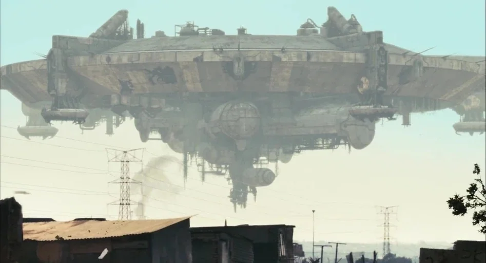 District 9 (2009) movie still: wide — A gargantuan, weathered metallic saucer hovers silently over a low-income shantytown district. Numerous…