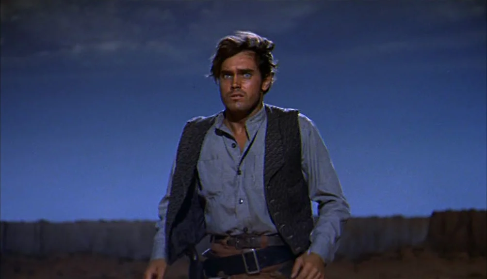 The Searchers movie still: medium — A man stands alone in a desert landscape under a dark night sky. He looks forward with his face lit by a bright…