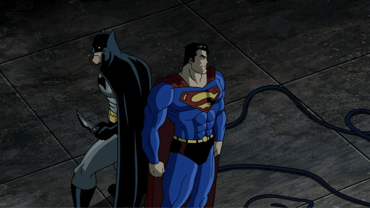 Superman/Batman: Public Enemies (2009) movie still: fullbody — Two costumed superheroes stand back to back on a large dark tiled surface. Batman…