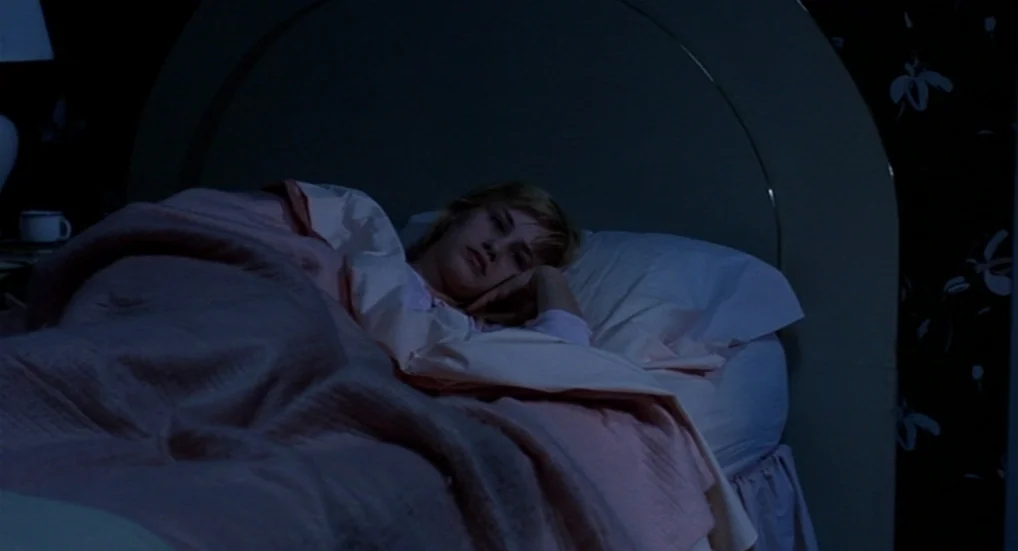 A Nightmare On Elm Street 3: Dream Warriors (1987) movie still: medium — A dark bedroom with floral patterned wallpaper features a woman lying in…