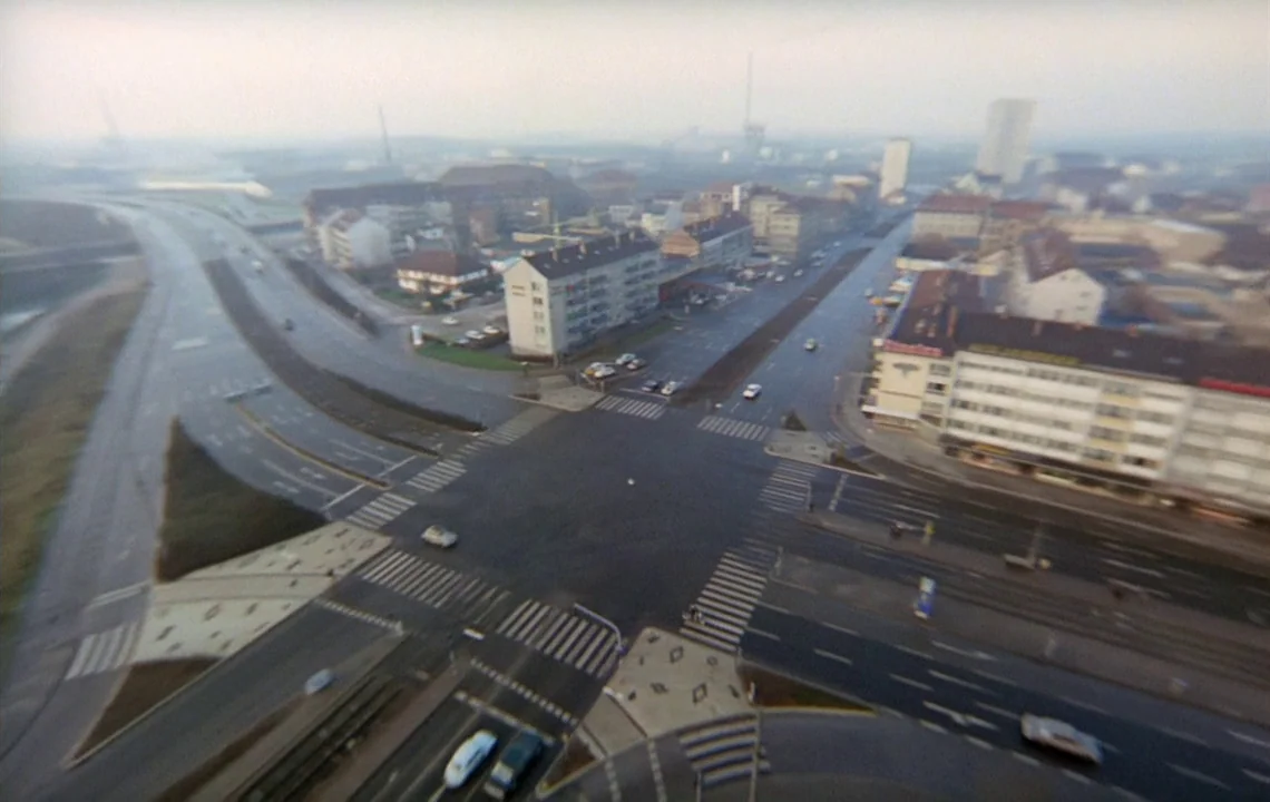 The Girl on a Motorcycle (1968) movie still: establishing — An aerial view of an urban intersection with wide paved roads and pedestrian crossings.…