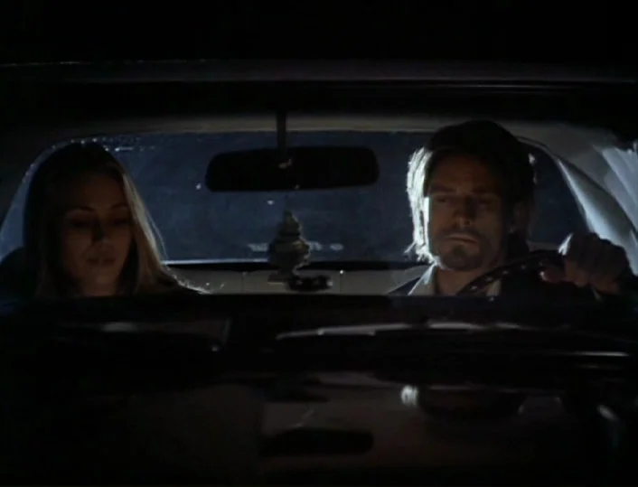Head of the Family (1996) movie still: medium — The interior of a car at night with two people sitting in the front. The man grips the steering…
