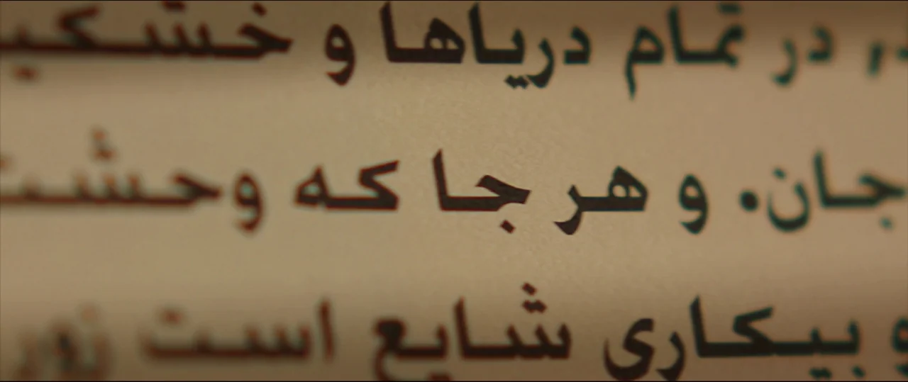Under The Shadow (2016) movie still: closeup — Close up on a printed page with Persian script in a dark typeface. The text is slightly blurred at…