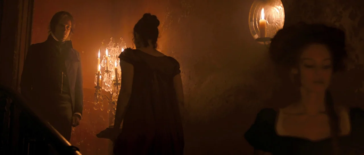 Byzantium (2012) movie still: medium — A dimly lit historical interior features a wooden staircase bathed in flickering candle light. A man and a…