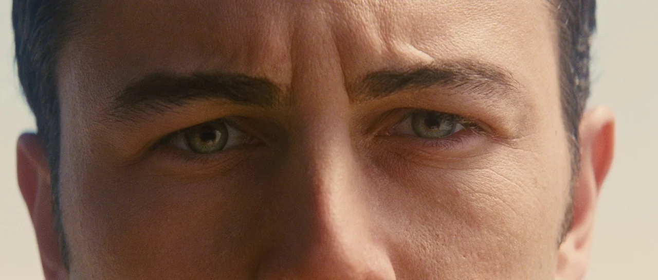 Looper (2012) movie still: closeup — A close-up shot focuses on the eyes and brow of a male subject. The subject looks directly into the lens under…