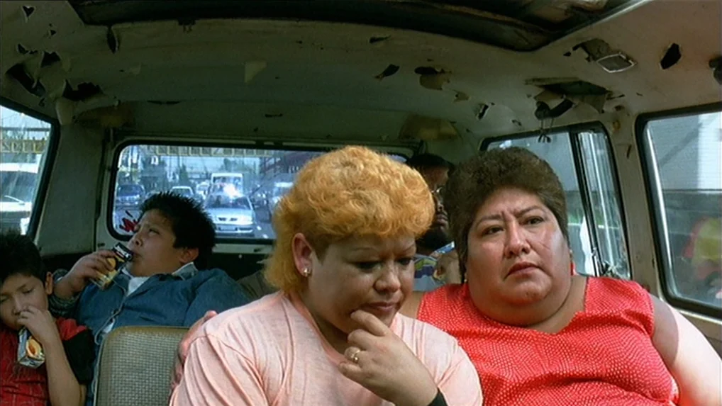Battle In Heaven (2005) movie still: medium — The interior of a worn van with peeling ceiling upholstery contains three passengers. A woman in a red…