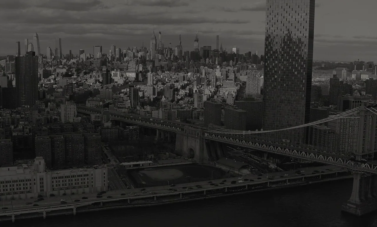 C’mon C’mon (2021) movie still: establishing — An aerial view shows the Manhattan skyline behind a suspension bridge and tall buildings. Multiple…