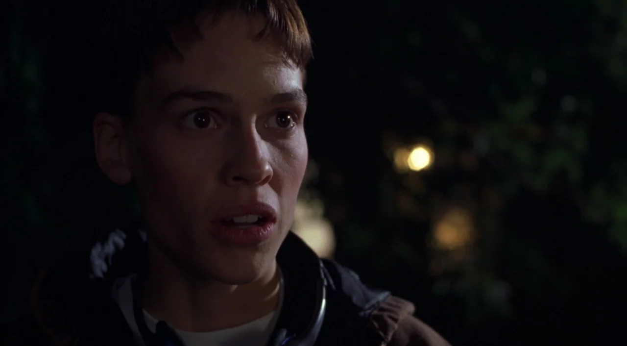 Boys Don’t Cry (1999) movie still: closeup — An outdoor setting at night features dark foliage obscured by shadows. The subject gazes ahead while…