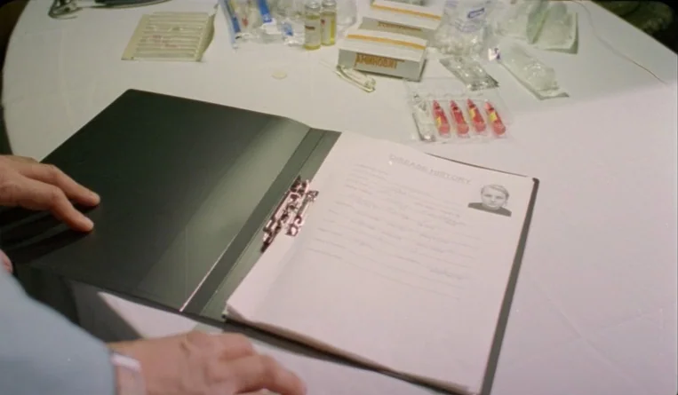 The Turn of the Century (2001) movie still: closeup — A white table is cluttered with various medical supplies and a disease history folder. The…