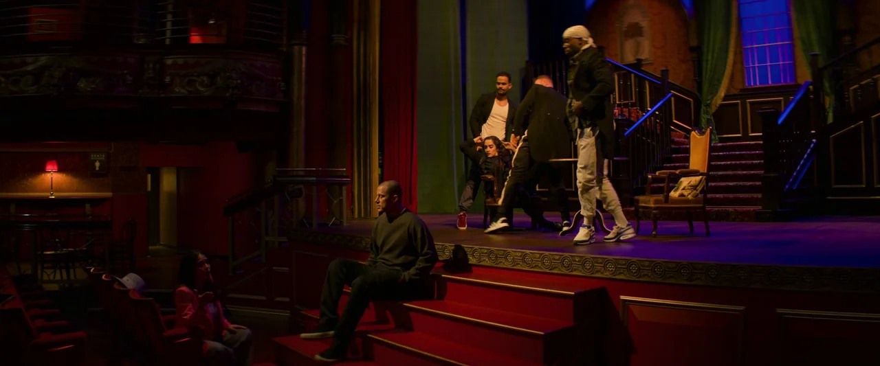 Magic Mike's Last Dance (2023) movie still: wide — A theatrical setting features a raised wooden platform and stairs in a dim auditorium. Five…
