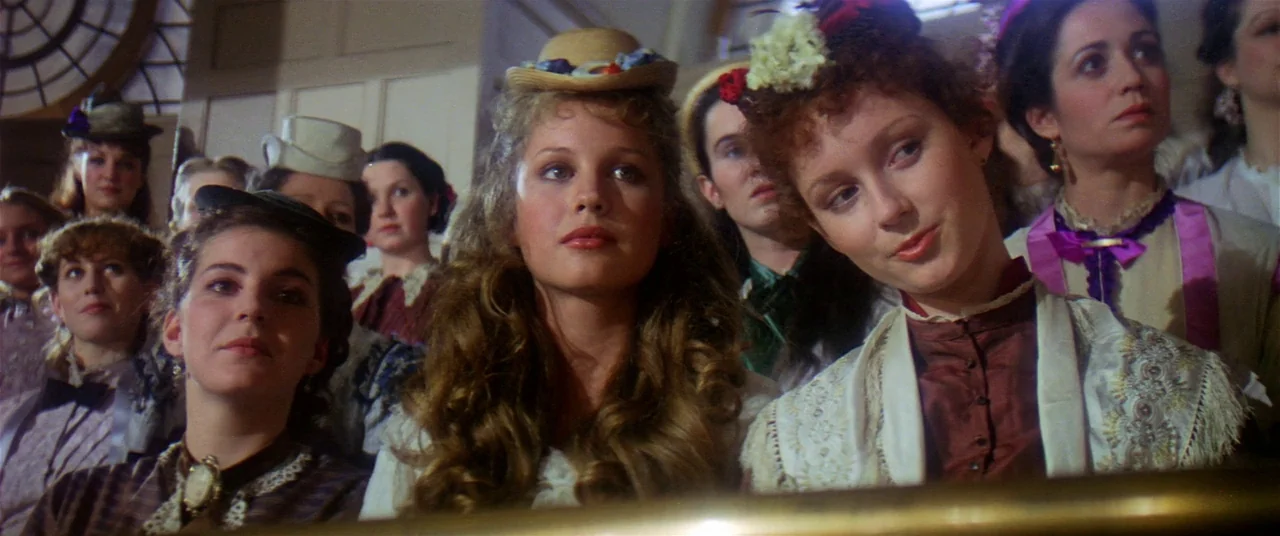 Heaven’s Gate (1980) movie still: medium — A group of women in 19th-century attire sit together in a wooden pew. They are gathered in a bright…