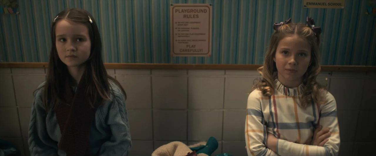 The Best Christmas Pageant Ever (2024) movie still: medium — A school hallway interior features light blue striped wallpaper and white tiled…