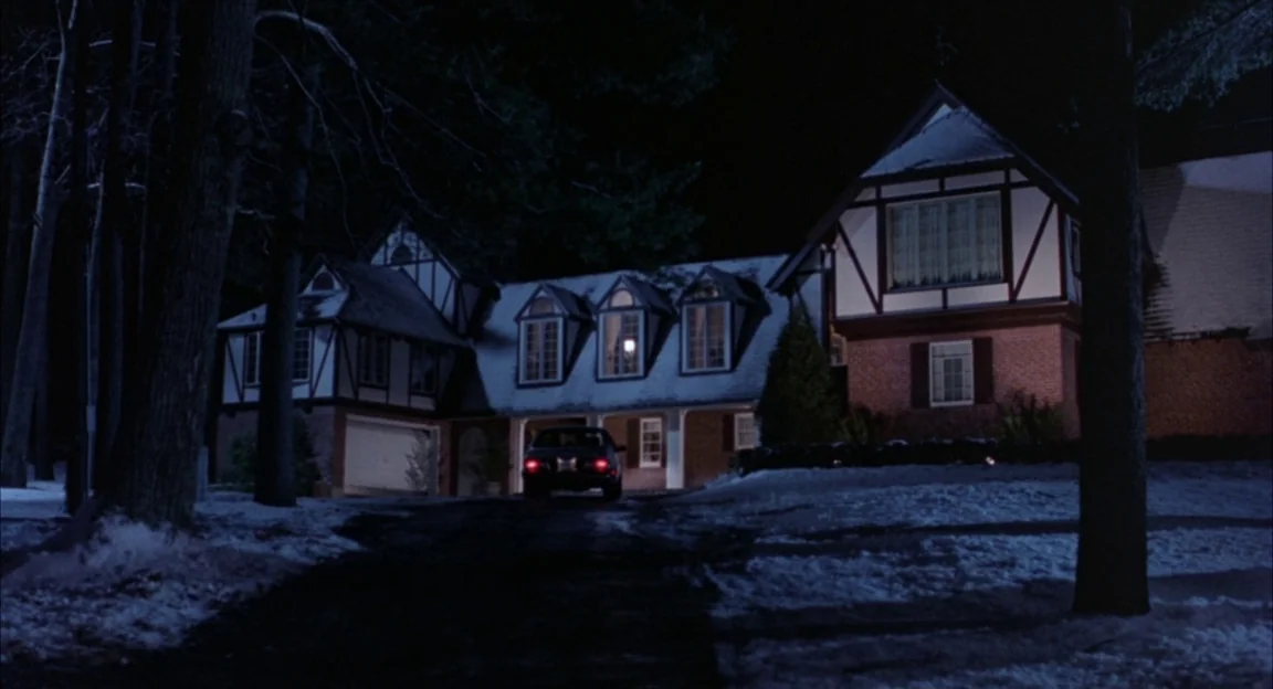 Creepshow 2 (1987) movie still: establishing — A dark two-story house with Tudor-style timber framing is visible at night. Snow lies on the driveway…