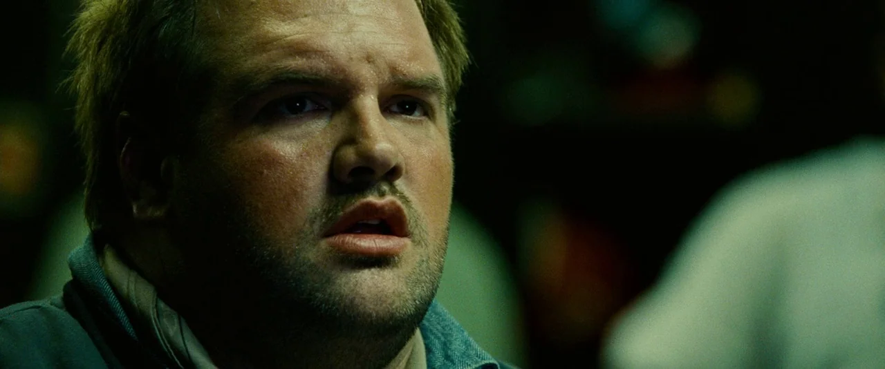 Unstoppable (2010) movie still: closeup — A close-up shot focuses on a man inside a dimly lit environment. He looks off-camera with wide eyes and a…