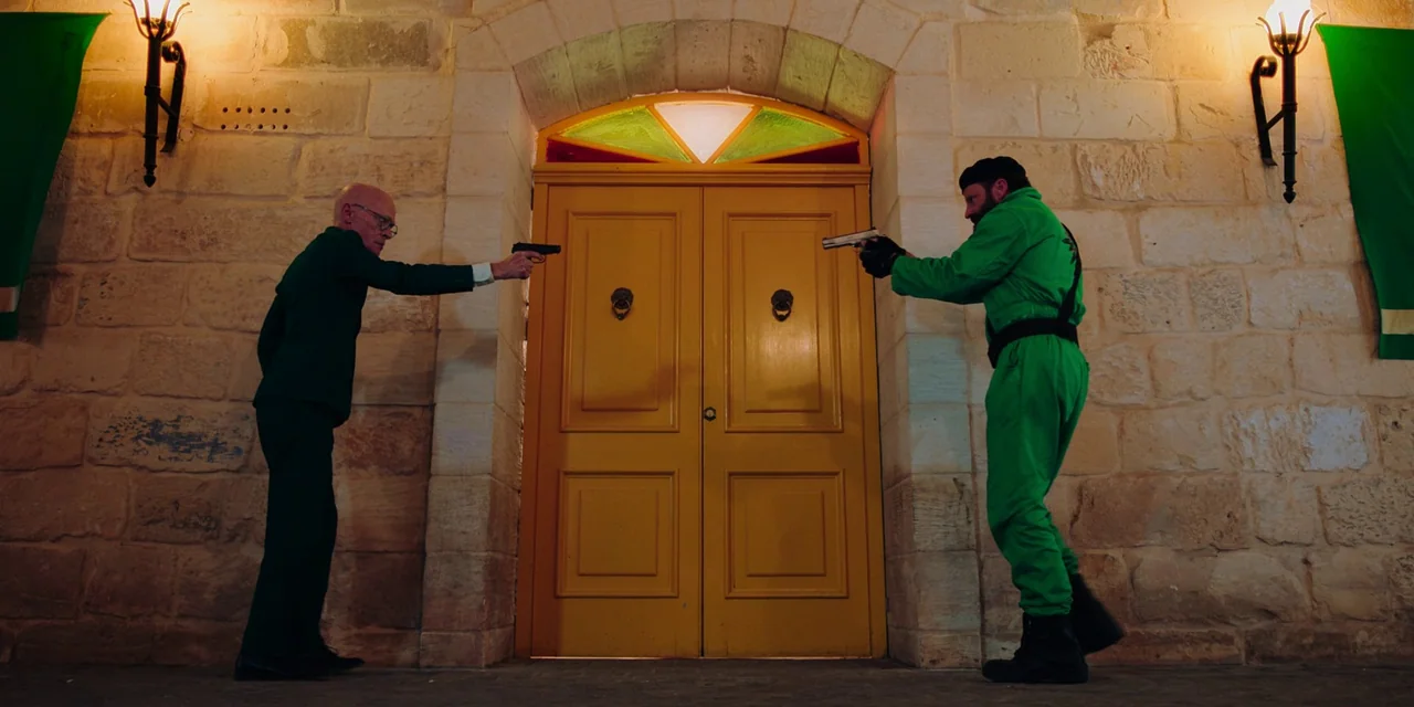 Sniper: G.R.I.T. (2023) movie still: fullbody — An interior stone wall features a central bright yellow door with a glass transom. Two men in green…