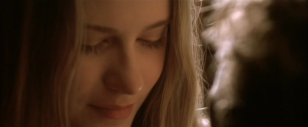 Down In The Valley (2005) movie still: closeup — A dimly lit interior space with warm lighting hitting the side of a face. A young woman with long…