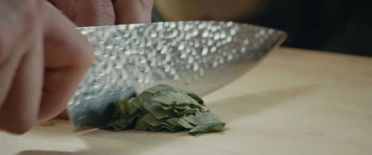 An emperor's jewel - The making of the Bulgari Hotel Roma (2024) movie still: closeup — A light wood cutting board sits on a countertop. A metal…