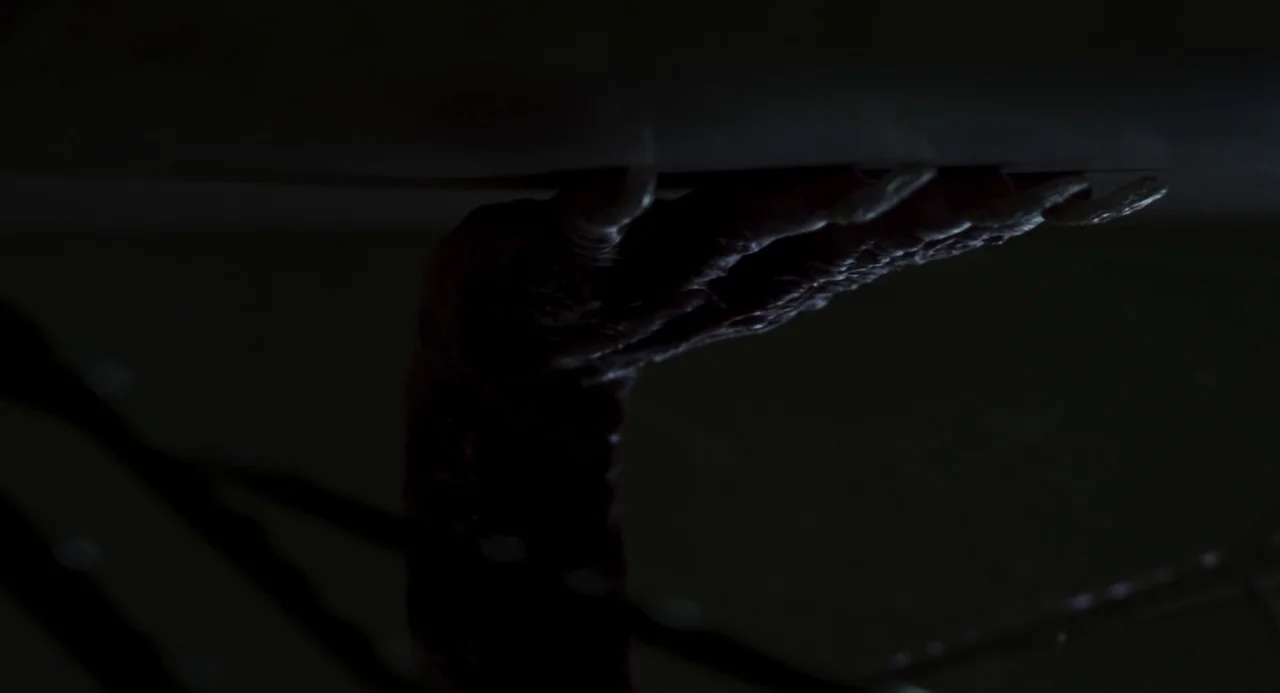 Suspiria (2018) movie still: closeup — A dark, textured creature's hand grips the edge of a flat horizontal surface. Long sharp claws are visible…
