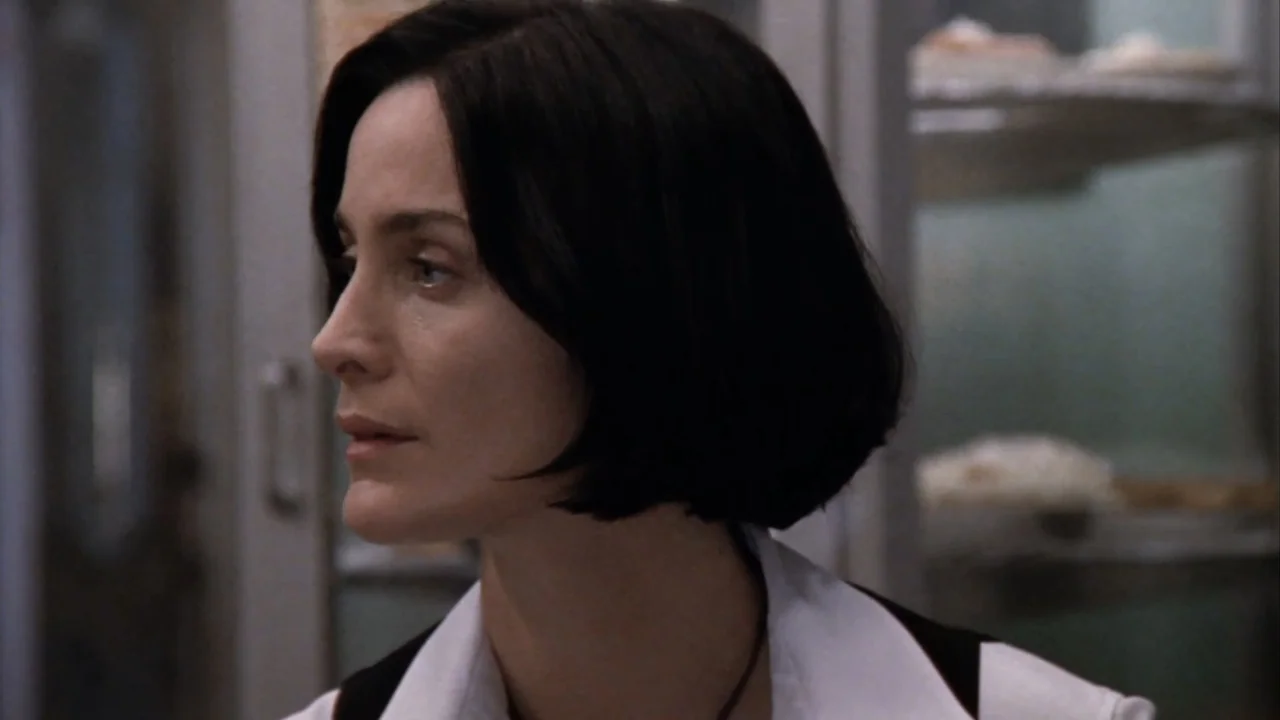 Suspect Zero (2004) movie still: closeup — A dimly lit indoor space featuring light-colored cabinetry in the background behind the subject. A woman…