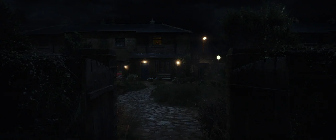 A Monster Calls (2016) movie still: establishing — A nighttime view of a suburban house front with a cobblestone path leading up. The yard is…