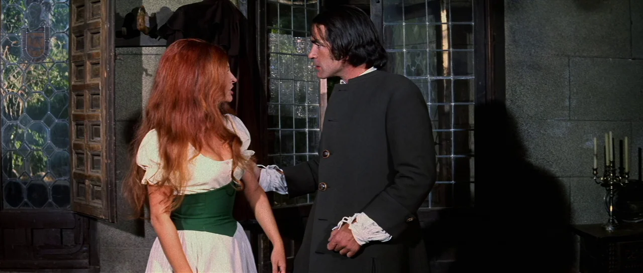 Night of the Blood Monster (1970) movie still: medium — A stone-walled interior with leaded glass windows and a candle holder on a table. A woman…