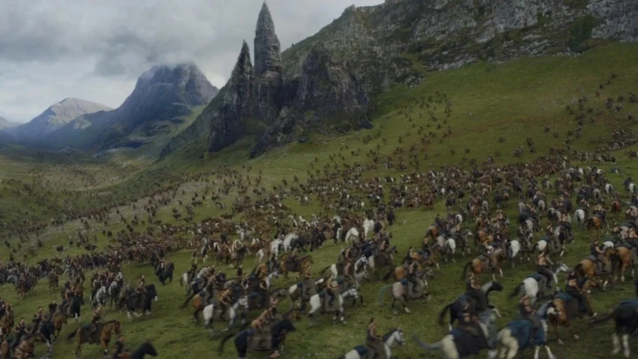 Game of Thrones (2015) movie still: wide — A vast grassy valley is flanked by tall, rocky, jagged mountain peaks. A massive army of horsemen rides…