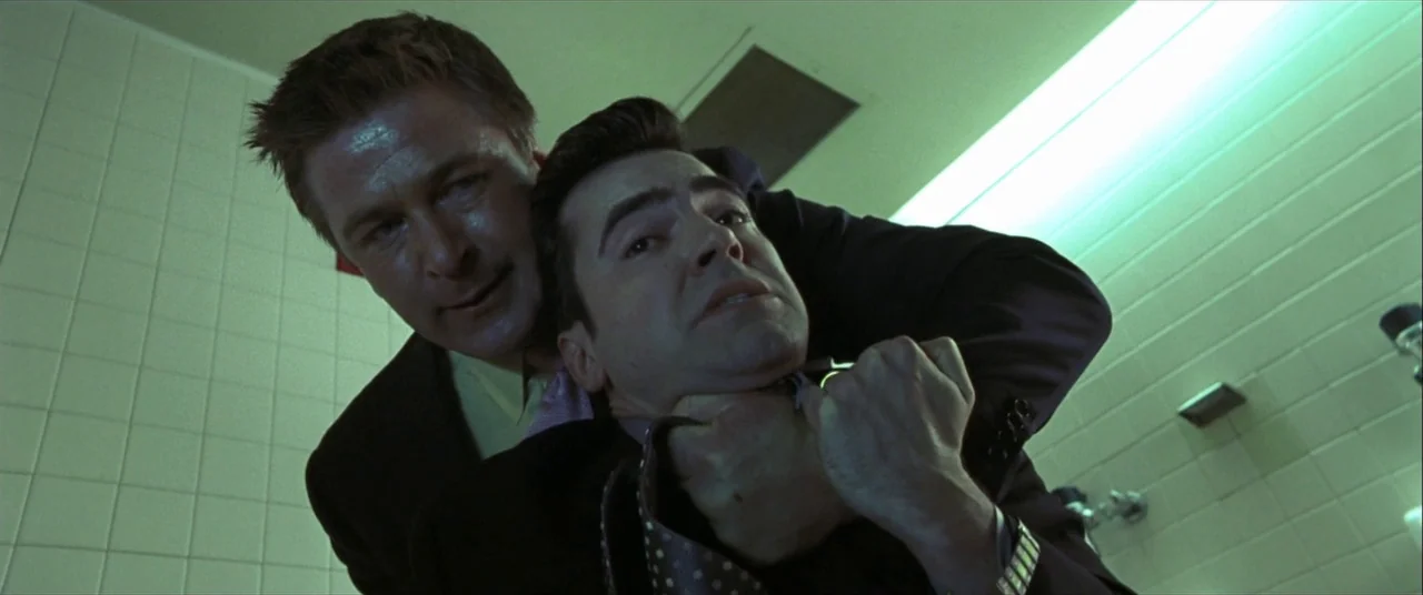 The Cooler (2003) movie still: medium — A tiled room with light-colored square wall tiles and harsh fluorescent lighting. One man grips the other by…