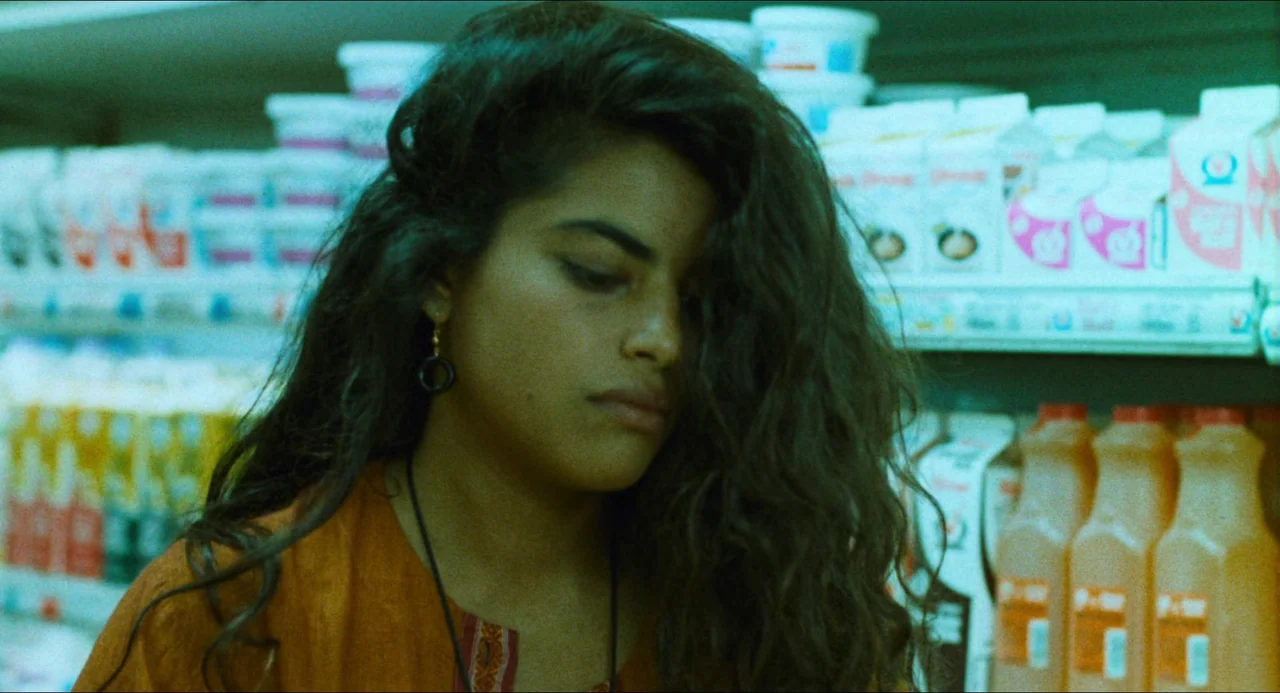 Mississippi Masala (1991) movie still: closeup — An aisle in a grocery store filled with rows of dairy and beverage products. A young woman with…