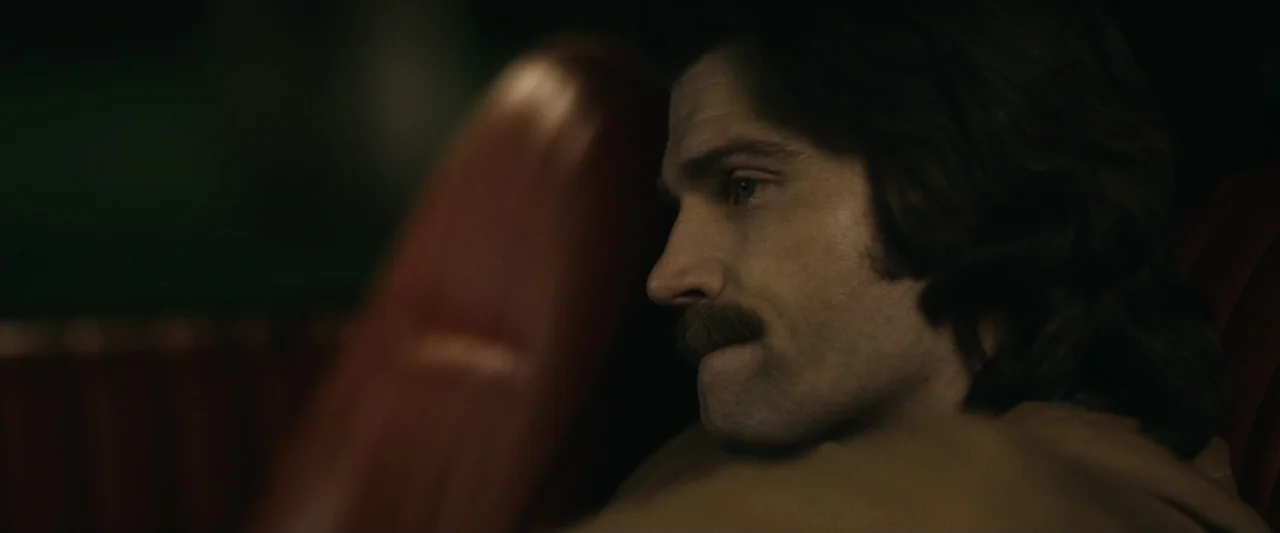 The Case for Christ (2017) movie still: closeup — The interior of a vehicle features red upholstery and dark shadow-filled surroundings. A man with…