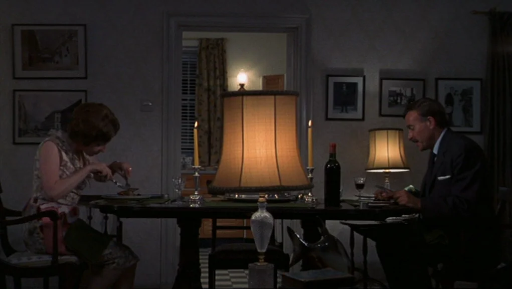 Frenzy (1972) movie still: medium — A dimly lit room features a formal wooden dining table with place settings. A couple dines in near silence with…