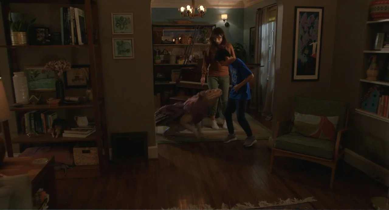 Harold and the Purple Crayon (2024) movie still: medium — A furnished living room with wooden floors, bookshelves, and a central doorway. A woman…