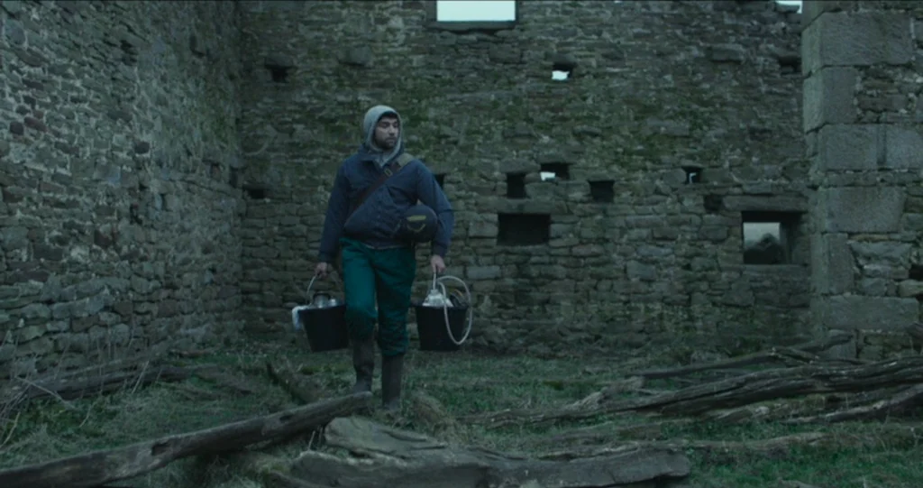 God’s Own Country (2017) movie still: fullbody — A stone structure has partial walls and numerous gaps allowing light to enter. A man in a hoodie…