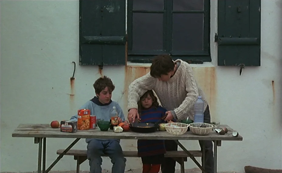 Kung Fu Master! (1988) movie still: fullbody — An outdoor area with a white stucco wall and green wooden shutters. Three children eat from a pan…