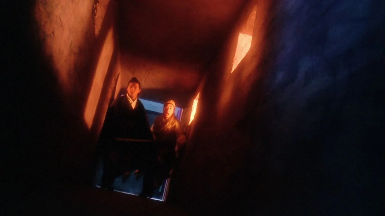 The Bride with White Hair II (1993) movie still: medium — A dark narrow stone passageway features square wall niches glowing with intense orange…