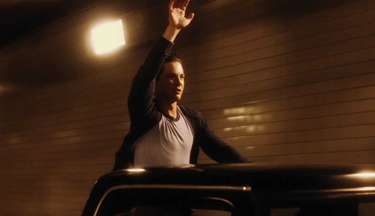 The Perks of Being A Wallflower (2012) movie still: medium — A man stands inside a vehicle, peering out from the sunroof within a dark tunnel. The…