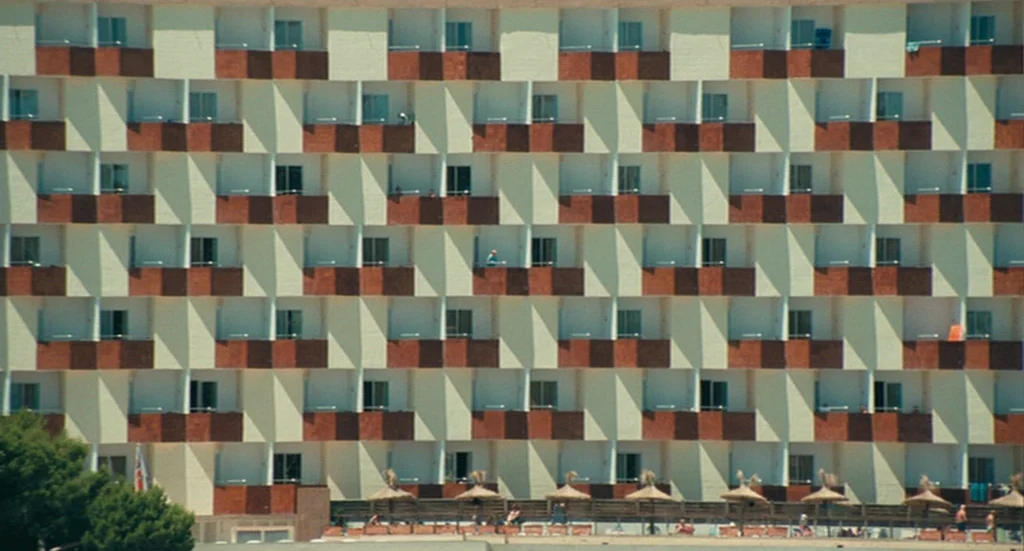 The Damned United (2009) movie still: establishing — A multi-story hotel facade features repetitive grid architecture with staggered recessed…