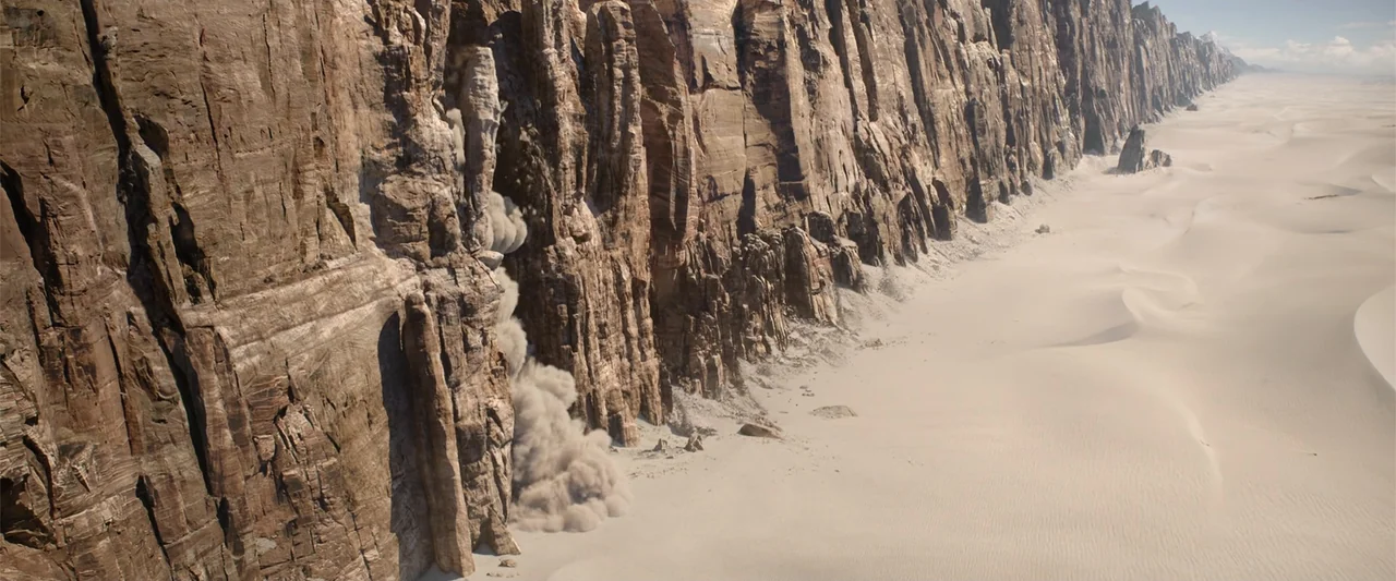 Jim Button and Luke the Engine Driver (2018) movie still: wide — A vast sandy desert borders an immense, towering rock formation under a bright sky.…
